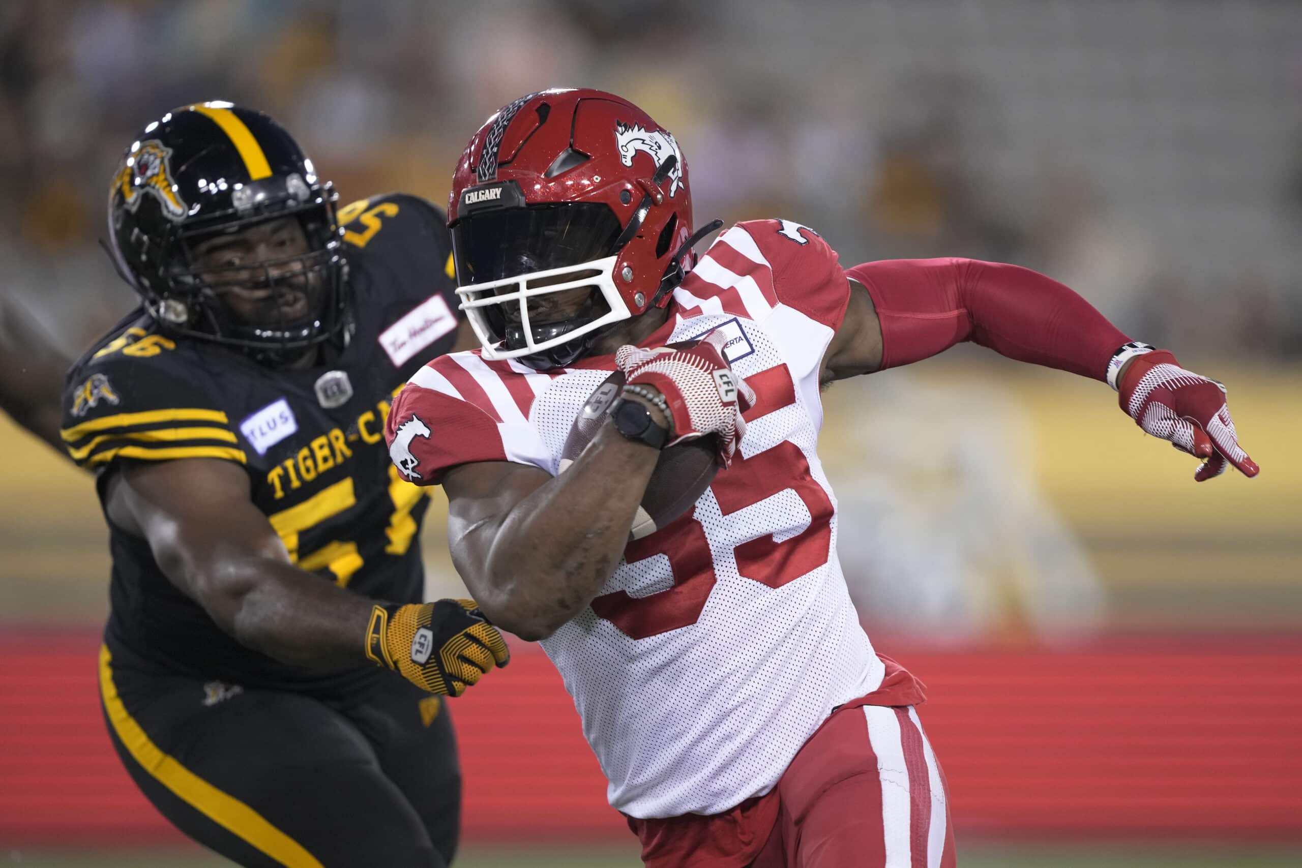 Part of our CFL teams list are the calgary stampeders. In the photo: HAMILTON, CANADA - SEPTEMBER 30: Ka'Deem Carey #35 of the Calgary Stampeders gets away from Ja'Gared Davis #56 of the Hamilton Tiger-Cats on a rushing play at Tim Hortons Field on September 30, 2023 in Hamilton, Canada. (Photo by John E. Sokolowski/Getty Images)