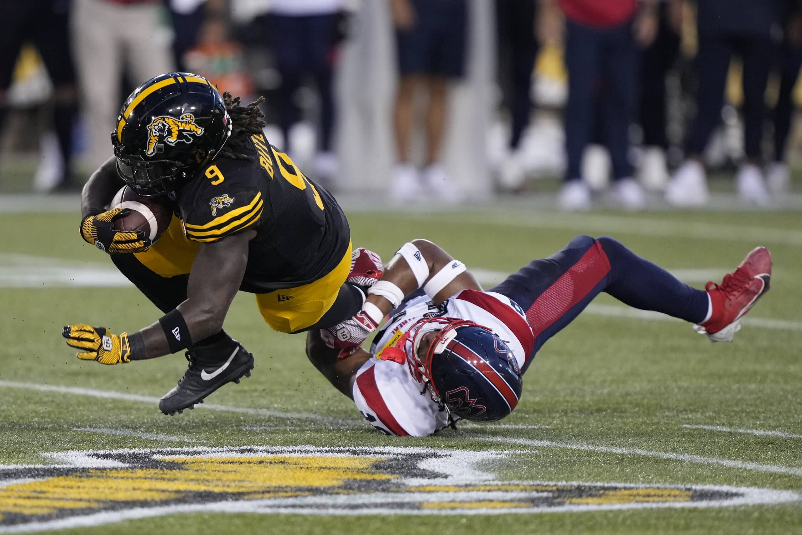 HAMILTON, CANADA - AUGUST 2: James Butler #9 of the Hamilton Tiger-Cats gets tackled by Geoffrey Cantin-Arku #19 of the Montreal Alouettes after a pass reception at Tim Hortons Field on August 2, 2024 in Hamilton, Canada.  (Photo by John E. Sokolowski/Getty Images)