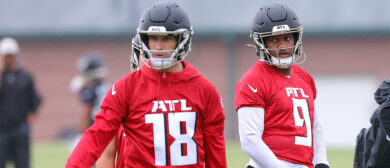 Quarterback Michael Penix Jr. #9 of the Atlanta Falcons looks on behind quarterback Kirk Cousins #18 during OTA offseason workouts at the Atlanta Falcons training facility on May 14, 2024 in Flowery Branch, Georgia.