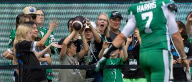 Fans catch a ball from Trevor Harris #7 of the Saskatchewan Roughriders during warmup before the game between the Hamilton Tiger-Cats and Saskatchewan Roughriders at Mosaic Stadium on June 23, 2024 in Regina, Canada.