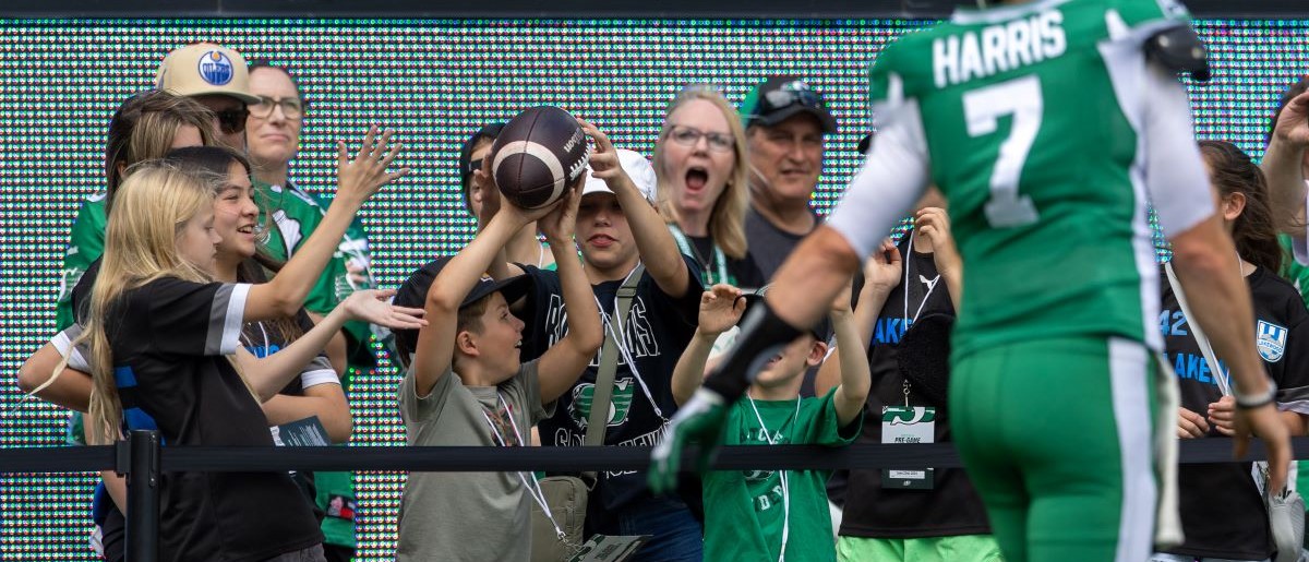 Fans catch a ball from Trevor Harris #7 of the Saskatchewan Roughriders during warmup before the game between the Hamilton Tiger-Cats and Saskatchewan Roughriders at Mosaic Stadium on June 23, 2024 in Regina, Canada.