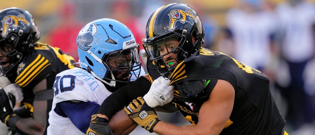 Jonathan Jones #30 of the Toronto Argonauts and Trevor Hoyte #42 of the Hamilton Tiger-Cats battle along the line of scrimmage on a punt at Tim Hortons Field on July 20, 2024 in Hamilton, Canada.