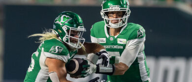 Trevor Harris #7 hands the ball off to AJ Ouellette #45 of the Saskatchewan Roughriders in the game between the Montreal Alouettes and Saskatchewan Roughriders at Mosaic Stadium on August 16, 2024 in Regina, Canada.