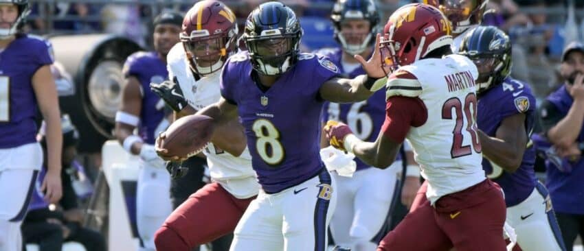 Baltimore Ravens quarterback Lamar Jackson (8) runs with the ball against Washington Commanders safety Quan Martin (20) during the NFL game between the Washington Commanders and the Baltimore Ravens on October 13, 2024 at M&T Bank Stadium in Baltimore, MD.