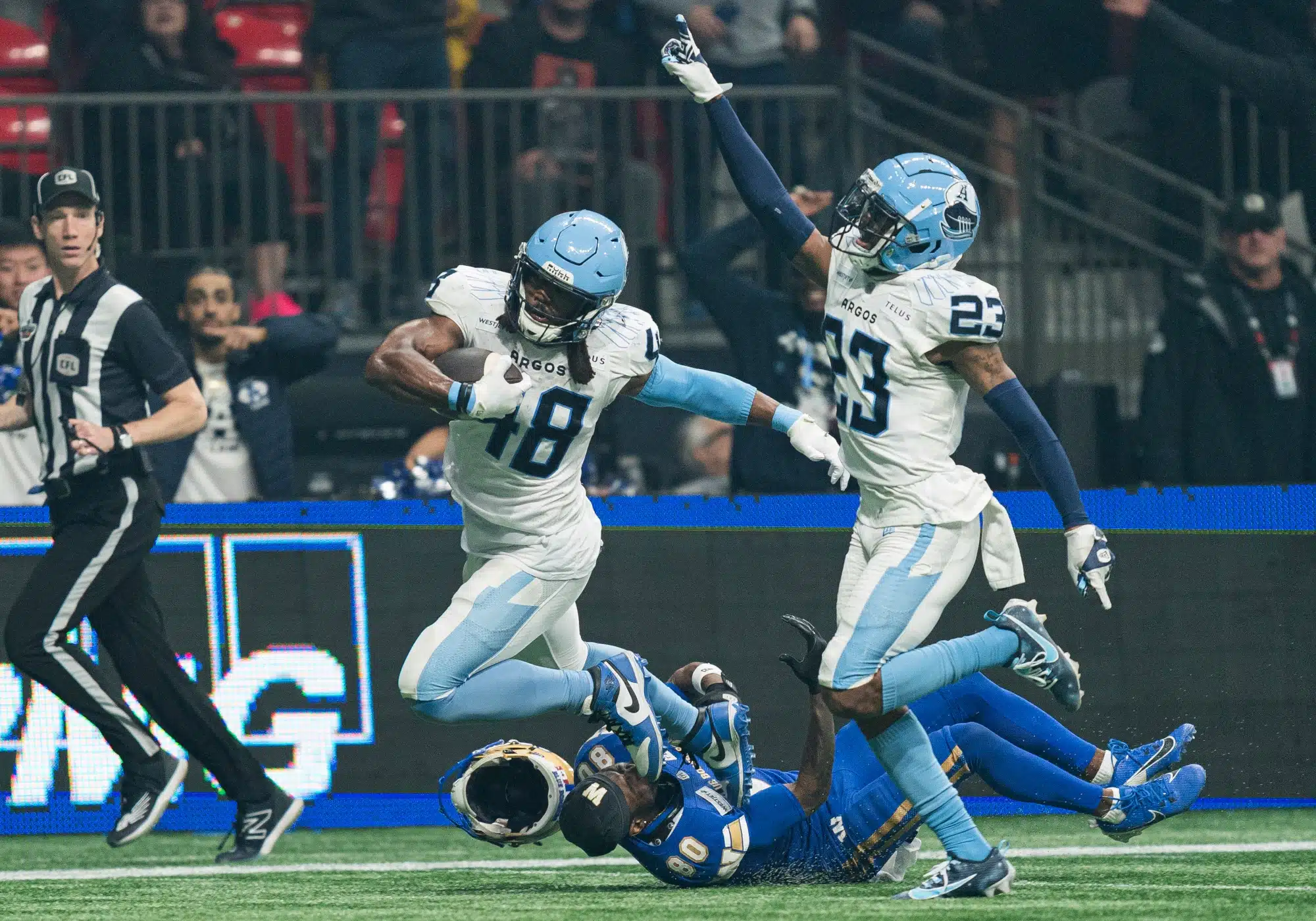 Wynton McManis #48 of the Toronto Argonauts is tripped up by Ontaria Wilson #80 of the Winnipeg Blue Bombers while returning an interception during the second half in CFL football action during the 2024 Grey Cup at BC Place on November 17, 2024 in Vancouver, Canada. Team mate Benjie Franklin #23 celebrates on the play.