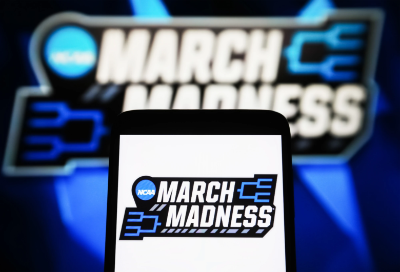 A March Madness (NCAA Division I men's basketball tournament) logo is seen on a smartphone and a PC screen.